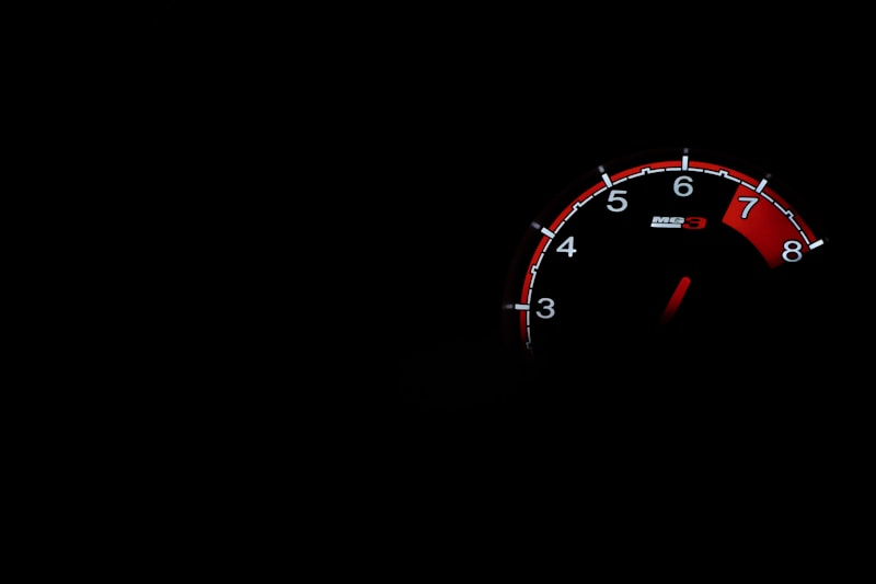 Tachometer on a dark dashboard with the needle climbing toward red